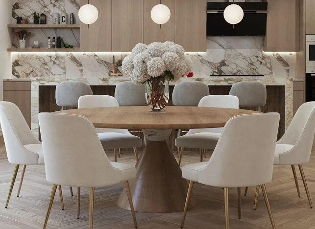 Modern Los Angeles dining room with round wood table, cream chairs, and marble kitchen backdrop