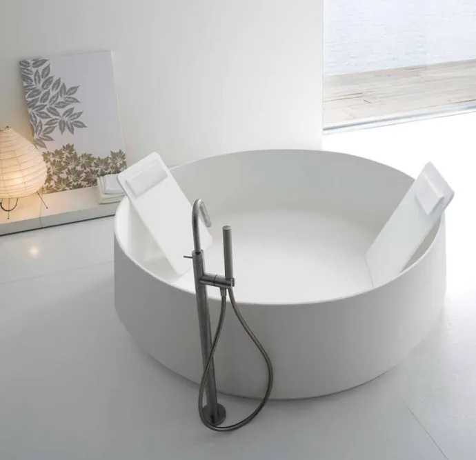 Round soaking tub with a modern freestanding faucet. 