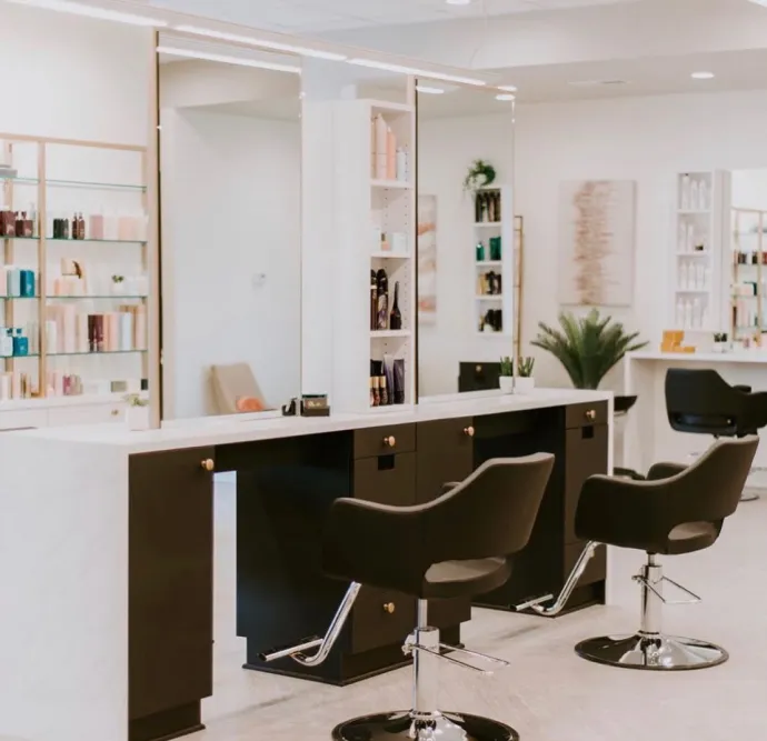 Sophisticated salon with sleek black chairs and large mirrors.