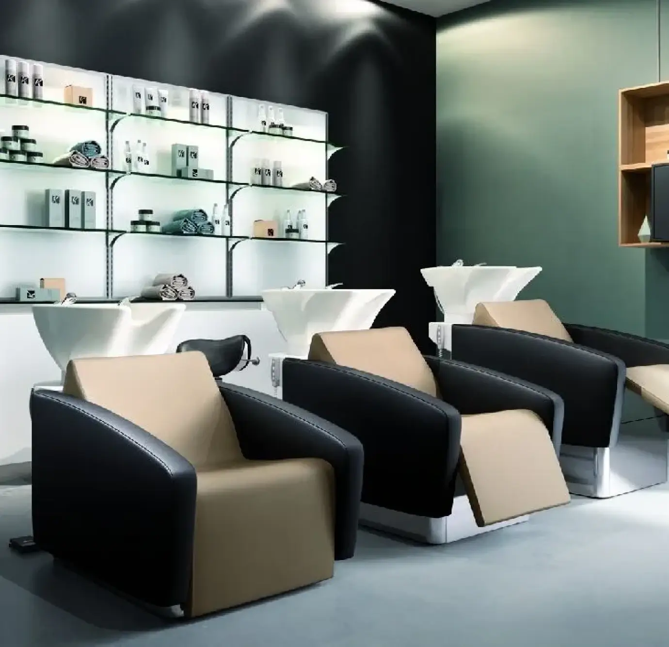 Modern hair salon shampoo bowl station with three black and beige leather reclining wash chairs, white ceramic basins, and illuminated glass retail 